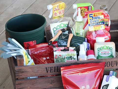 木製テーブルに置かれた剪定バサミとローション、バラの花